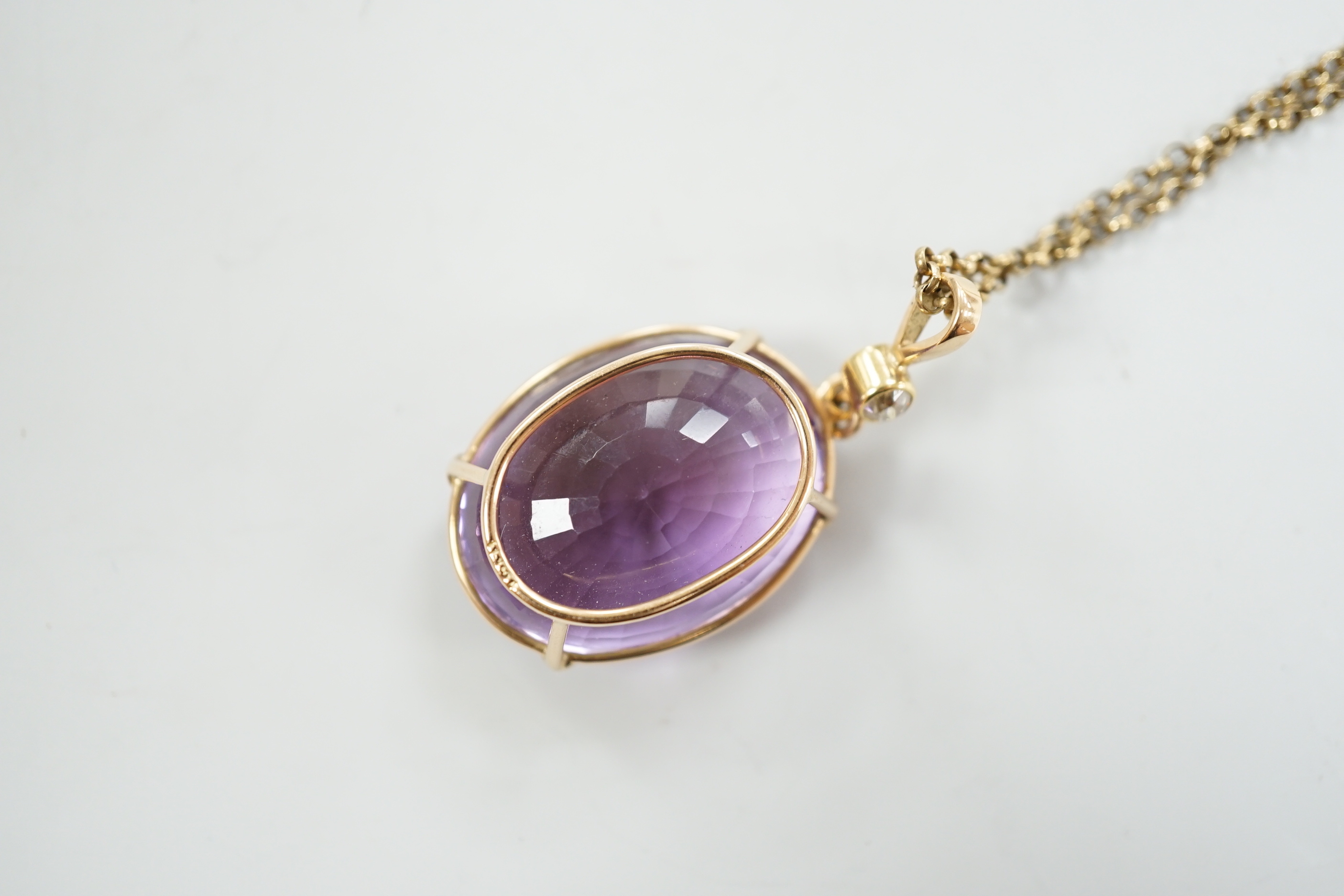 An early 20th century 15ct and single stone oval cut amethyst set pendant, with single stone diamond set bale, overall 42mm, on a gold plated chain.